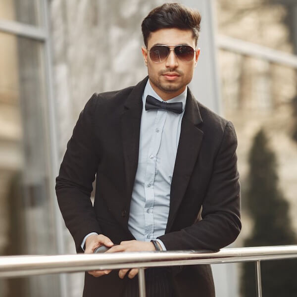 fashionable you man makes a first impression with dark glasses, bow tie, and suit.